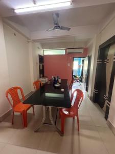 ein Esszimmer mit einem schwarzen Tisch und orangefarbenen Stühlen in der Unterkunft ROOP AMRIT GUEST HOUSE in Agartala