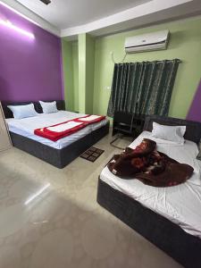 2 Betten in einem Zimmer mit lila und grünen Wänden in der Unterkunft ROOP AMRIT GUEST HOUSE in Agartala