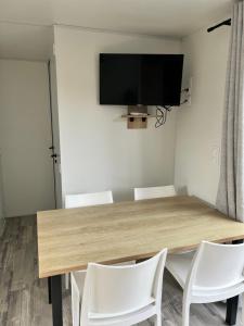 stół jadalny z białymi krzesłami i telewizor z płaskim ekranem w obiekcie Mobilhome Camping Biscarrosse 5 étoiles bord du lac w mieście Biscarrosse