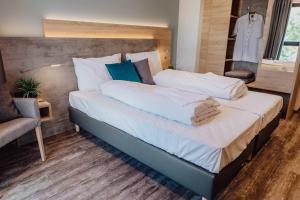 a bedroom with a large bed with white sheets and blue pillows at Pascals Ruhestube in Mörsdorf