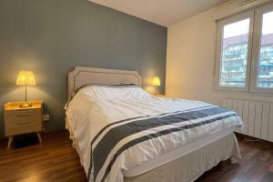 a bedroom with a bed and two lamps and a window at Le Pegan - Appartement 2 chambres proche du centre de Ferney et de Palexpo in Ferney-Voltaire