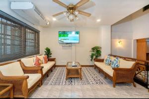 uma sala de estar com mobiliário em vime e uma ventoinha de tecto em Solene Home Patong em Praia de Patong