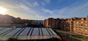 a view of a city with buildings and the sun at Casa Blikstad, Con Wifi y Garaje · 3 hab - 6 pax in Gijón
