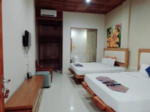 a hotel room with two beds and a television at Crystal Beach Bali in Candidasa