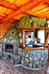 a stone fireplace in a kitchen in a log cabin at Domek u Johnnego 27 in Piwniczna-Zdroj
