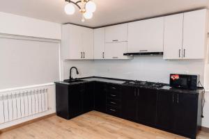 a kitchen with white cabinets and a black counter top at Villa Belle in Tashkent City in Tashkent