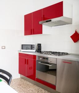 a kitchen with red cabinets and a stove top oven at La Ginestra - between lake and mountains in Colazza