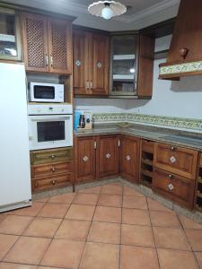 una cocina con armarios de madera y un aparato blanco en Habitaciones La Flamenka en Ronda