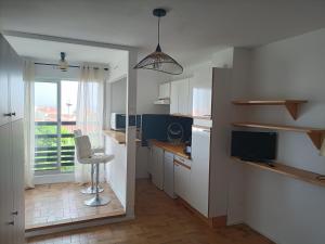 a kitchen with white cabinets and a chair and a window at Saint-Cyprien plage, charmant studio meublé vue mer in Saint-Cyprien