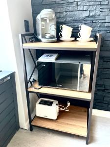 a microwave on a shelf with a toaster and cups at Apartament Kaja in Siemianowice Śląskie