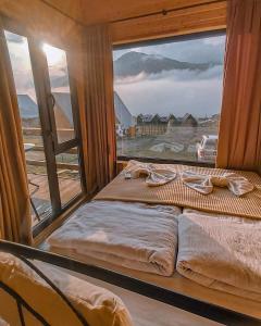two beds in a room with a large window at Kazbegi Twins in Kazbegi