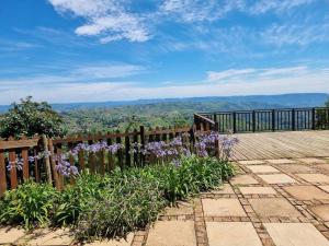 a wooden deck with purple flowers and a fence at 11-on-RobRoy calming space with 3 bedrooms&pool in Hillcrest