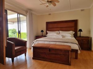 a bedroom with a bed and a chair and a window at 11-on-RobRoy calming space with 3 bedrooms&pool in Hillcrest