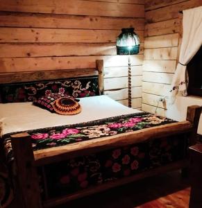 Una cama en una cabaña de madera con una lámpara. en Cabana Kraus, en Valea Vişeului