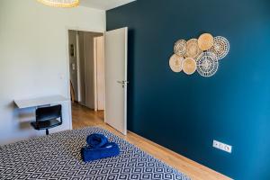 a bedroom with a blue wall with a bed and a desk at L'aparté - Centre ville Lens - Gare in Lens