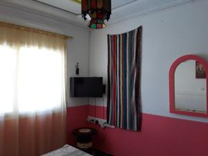 - une chambre avec un lit, un miroir et une télévision dans l'établissement Maison d'Hôte à Saïdia, à Saïdia