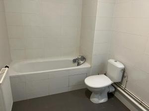 a white bathroom with a toilet and a bath tub at Appartement idéalement placé in Villeparisis