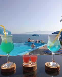 3 vasos en una mesa junto a una piscina en Apartments Romario, en Sarandë