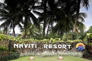 una señal para un complejo con palmeras en el fondo en The Naviti Resort en Korolevu