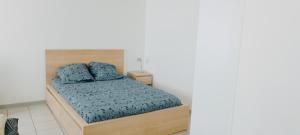 Denain的住宿－Superbe studio cosy spacieux au rez de chaussée，一间卧室配有一张带蓝色枕头的木床。