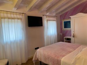 1 dormitorio con 1 cama y TV de pantalla plana en Romantica camere Le Fate con Vista sulle Montagne vicino a Bassano del Grappa, en Romano D'Ezzelino