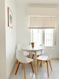 Biały stół i krzesła w pokoju z oknem w obiekcie El Gato Gris w mieście Conil de la Frontera