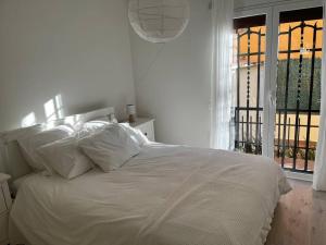 Cama blanca con almohadas blancas y ventana en Precioso Bajo en 2a línea de mar, en Segur de Calafell