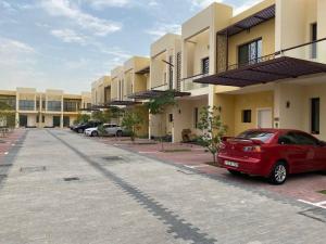 ein rotes Auto, das vor einem Gebäude parkt in der Unterkunft Family-Friendly Villa 1br with Play Area+Pool. UAE in Dubai
