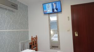 baño con TV en la pared y espejo en Pensión O Escondidino, en Baiona