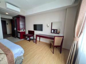 a hotel room with a bed and a desk with a mirror at Asialink Premier hotel in Karawang