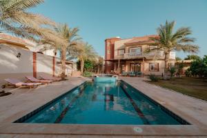 a swimming pool in front of a house with palm trees at Luxury private villa with pool in Hurghada