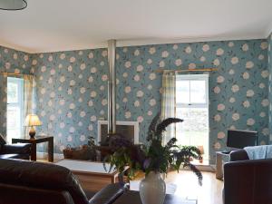 a living room with a flowery wallpaper and a couch at The Kennels Bothy - Beaufort Estate in Belladrum