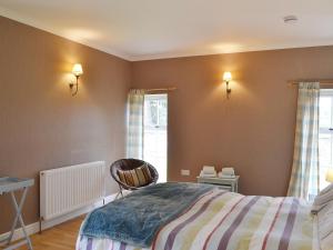 a bedroom with a bed and a chair and a window at The Kennels Bothy - Beaufort Estate in Belladrum