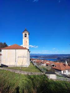a church with a clock tower on a hill at La Ginestra - between lake and mountains in Colazza
