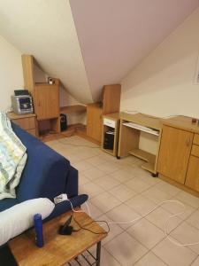 ein Wohnzimmer mit einem blauen Sofa und einem Schreibtisch in der Unterkunft Appartement Huldange in Huldange