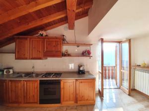 uma cozinha com armários de madeira e um forno com placa de fogão em Pleasant apartment in Vendrogno with balcony em Regoledo