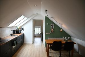 eine Küche mit einem Tisch und einer grünen Wand in der Unterkunft Appartementen Chaamse Bossen met tuin in Chaam