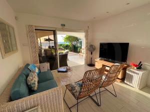 a living room with a couch and chairs and a television at Caro's Beachfront in Trou aux Biches