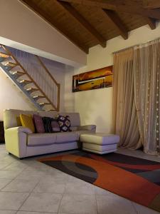 a living room with a couch and a staircase at La Mansarda del Viandante in Castelbelforte