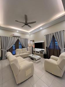 uma sala de estar com sofás e uma televisão de ecrã plano em Entire Vacation Home with landscape garden em Sitiawan