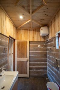 a bathroom with a sink and a toilet and a door at THE HIMALAYAN WOODS, CHAUKORI in Chaukori