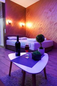 um quarto com uma mesa com um copo de vinho e uma cama em Wonderland spa apartment em Niš