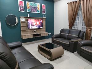 a living room with couches and a flat screen tv at D'Kampung Homestay Melaka in Melaka