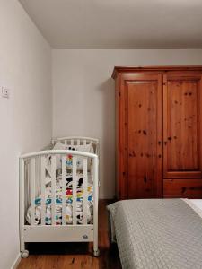 ein weißes Kinderbett in einem Schlafzimmer mit einem Holzschrank in der Unterkunft Casa da Maria, Montegrazie (IM) in Montegrazie
