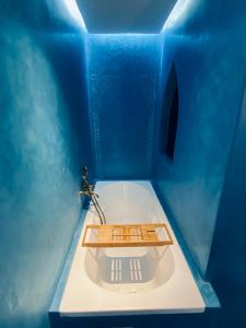 baño azul con bañera y bandeja de madera. en Stunning Apartment - Panoramic pool view en Marrakech