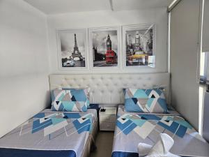 duas camas num pequeno quarto com quadros na parede em Spacious Studios em Manila