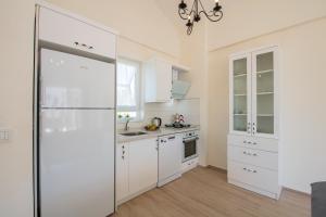 SunTeos Villa Suites في فتحية: مطبخ مع دواليب بيضاء وثلاجة