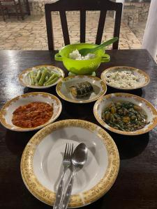 a table with plates and bowls of food on it at Home Stay Ramli in Bira