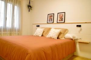 1 dormitorio con 1 cama grande de color naranja y 2 almohadas en Apartamento Brisas, en Moaña