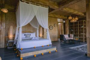a bedroom with a bed with a canopy at Makerti Bali~Bamboo House in Selat